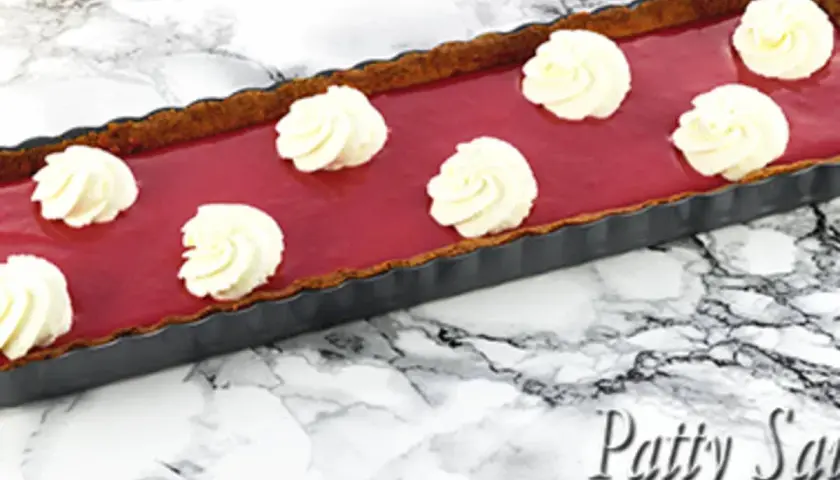 Tarte rectangulaire au curd framboise, garnie de touches de crème fouettée. Un délice fruité et gourmand.