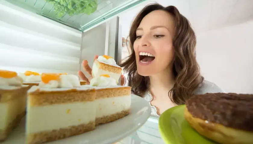 Une femme regarde des parts de gâteau à la crème pâtissière dans un réfrigérateur. Peut-on congeler une tarte à la crème pâtissière ?