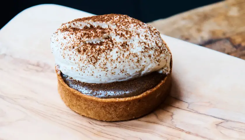 Tartelette gourmande avec une généreuse crème pour gâteau, saupoudrée de cacao. Un délice visuel.