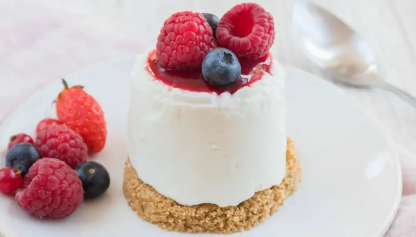 Délicieux dessert sans cuisson, un petit gâteau crémeux garni de fruits rouges frais et d'un coulis.