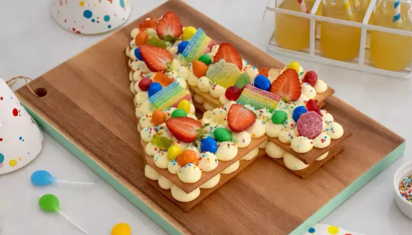Un délicieux number cake sans crème, décoré de fraises, bonbons et vermicelles colorés, parfait pour une fête d'anniversaire.