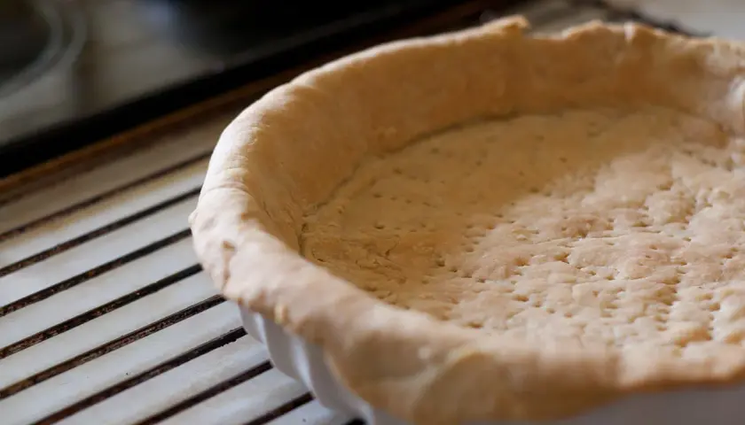 Pâte brisée crue dans un moule, prête à être garnie. Attention à la péremption de la pâte brisée pour une cuisson parfaite.