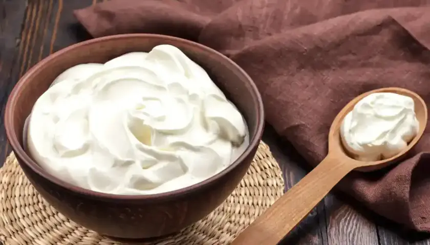 Crème diplomate onctueuse dans un bol, prête pour une recette gourmande. Une cuillère en bois en présente une portion.