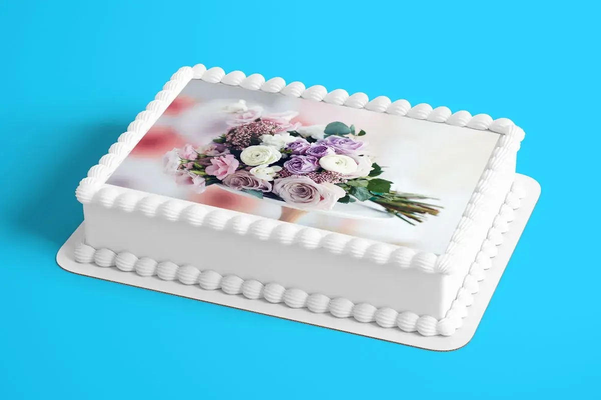 Gâteau blanc décoré d'un bouquet de fleurs roses et violettes sur une feuille azyme. Parfait pour une recette festive.