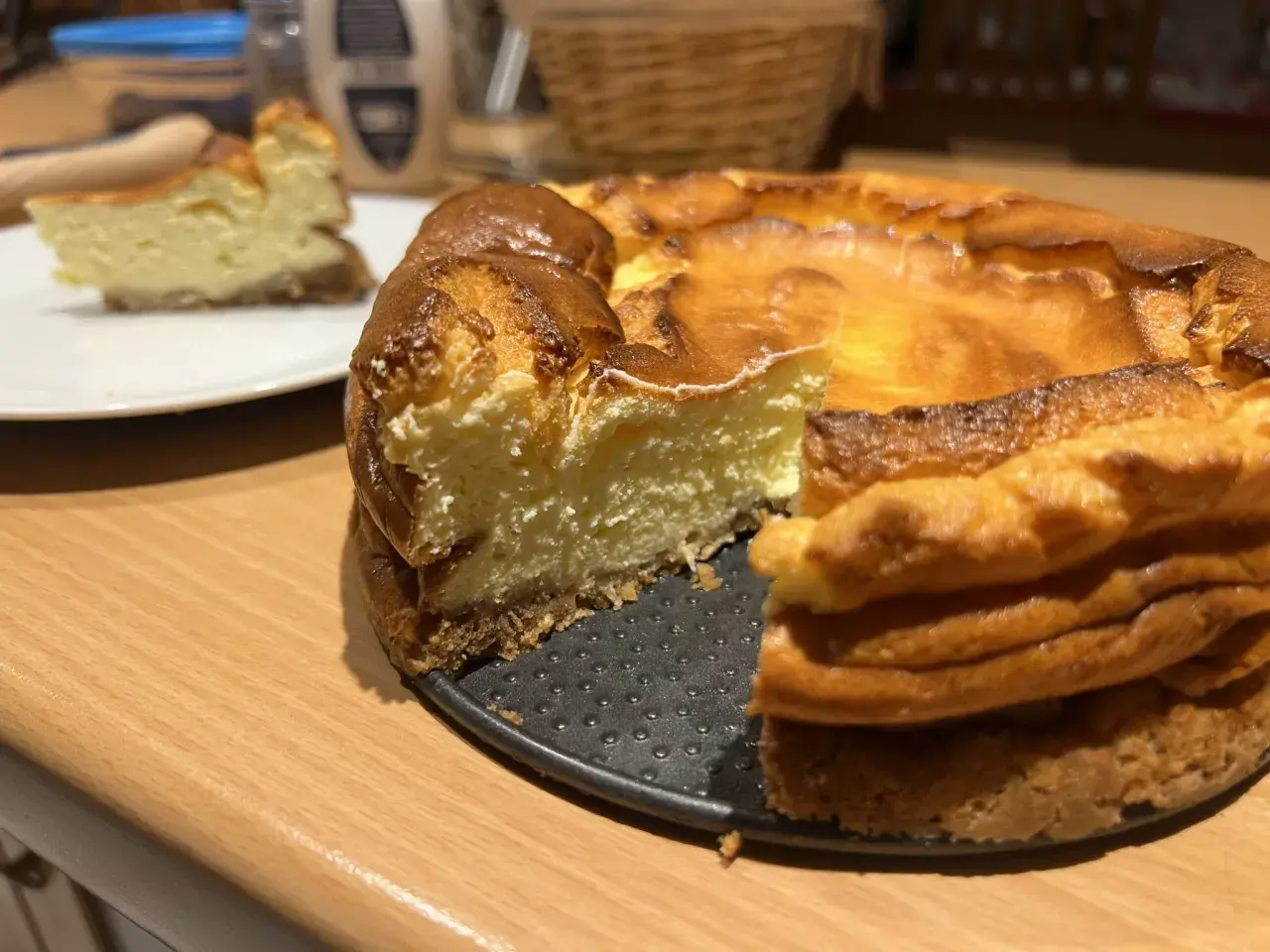 Un délicieux gâteau healthy, un cheesecake doré et crémeux, avec une part déjà servie sur une assiette blanche.