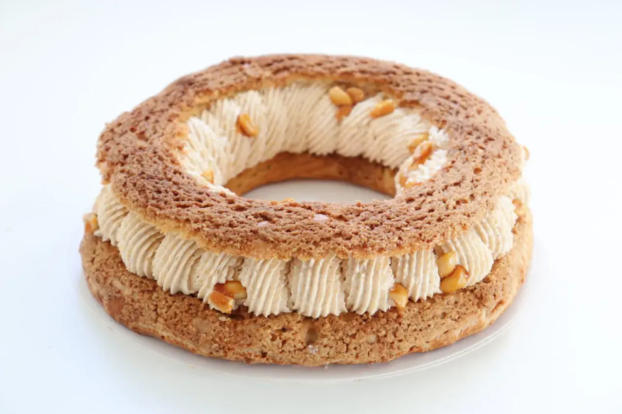 Un Paris-Brest rond, garni d'une crème onctueuse et parsemé de morceaux de praliné cacahuète croquant.