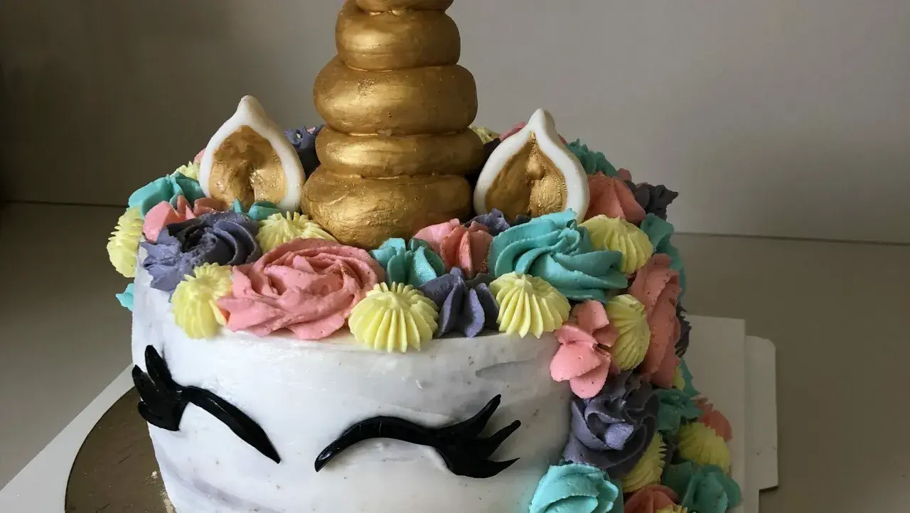 Un gâteau licorne facile sans pâte à sucre, décoré de crème colorée et d'une corne dorée. Parfait pour une fête magique !