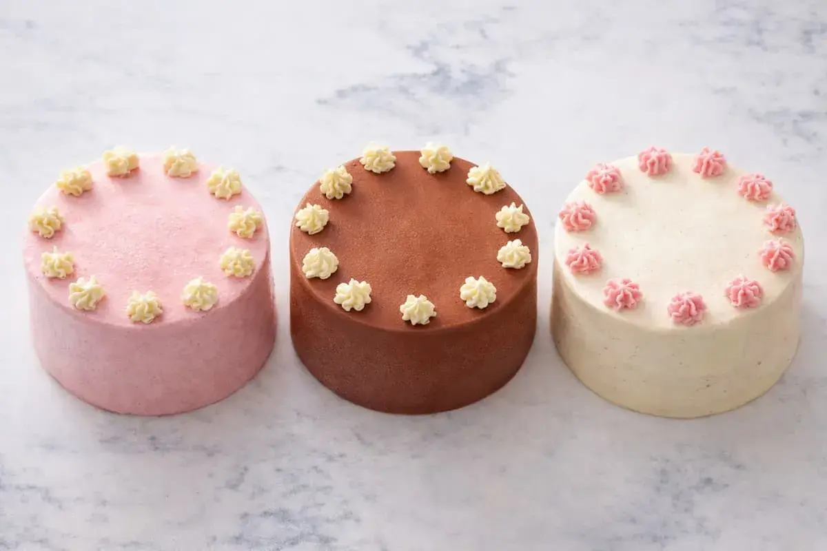 Trois petits gâteaux, une recette bento cake : rose, chocolat et vanille, décorés de crème.