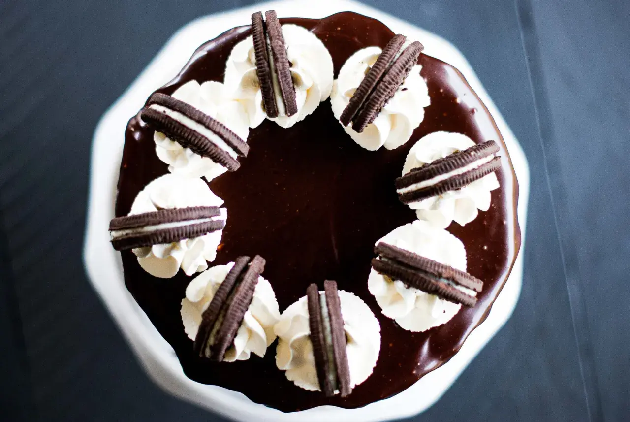 Gâteau au chocolat glacé, décoré de crème fouettée et de biscuits Oreo. Un délice pour les amateurs de layer cake Oreo.