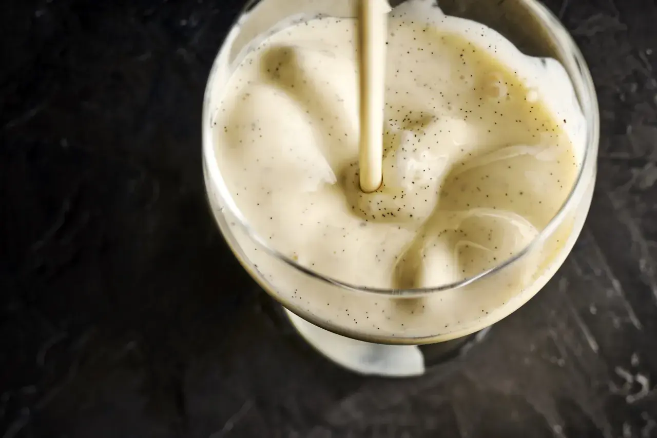 Crème vanillée versée dans un verre, évoquant la différence entre crème anglaise et pâtissière.
