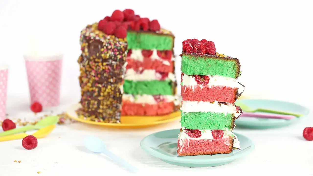 Gâteau coloré aux couches de pistache et framboise, garni de fruits rouges frais.
