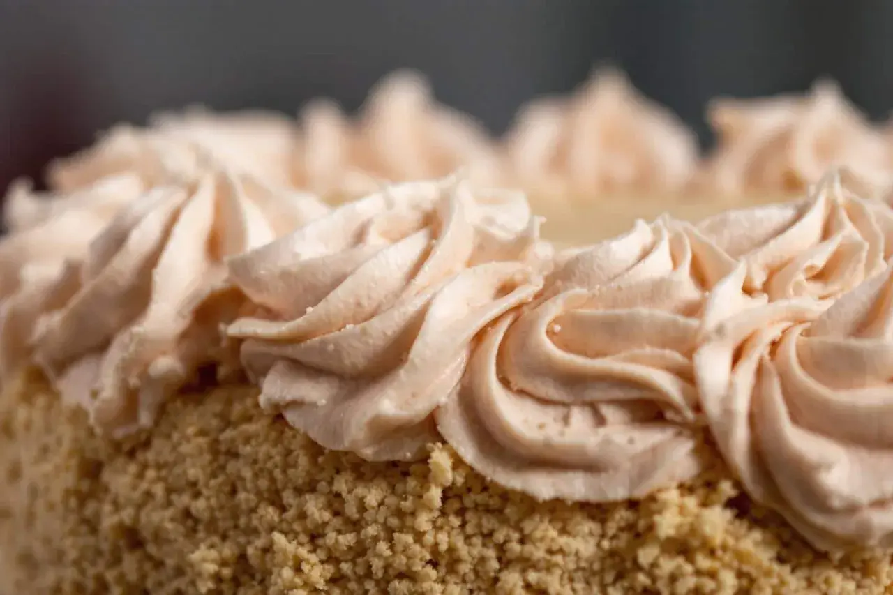Gâteau recouvert de miettes et décoré de volutes de crème rose pâle. Une décoration gateau facile et élégante.
