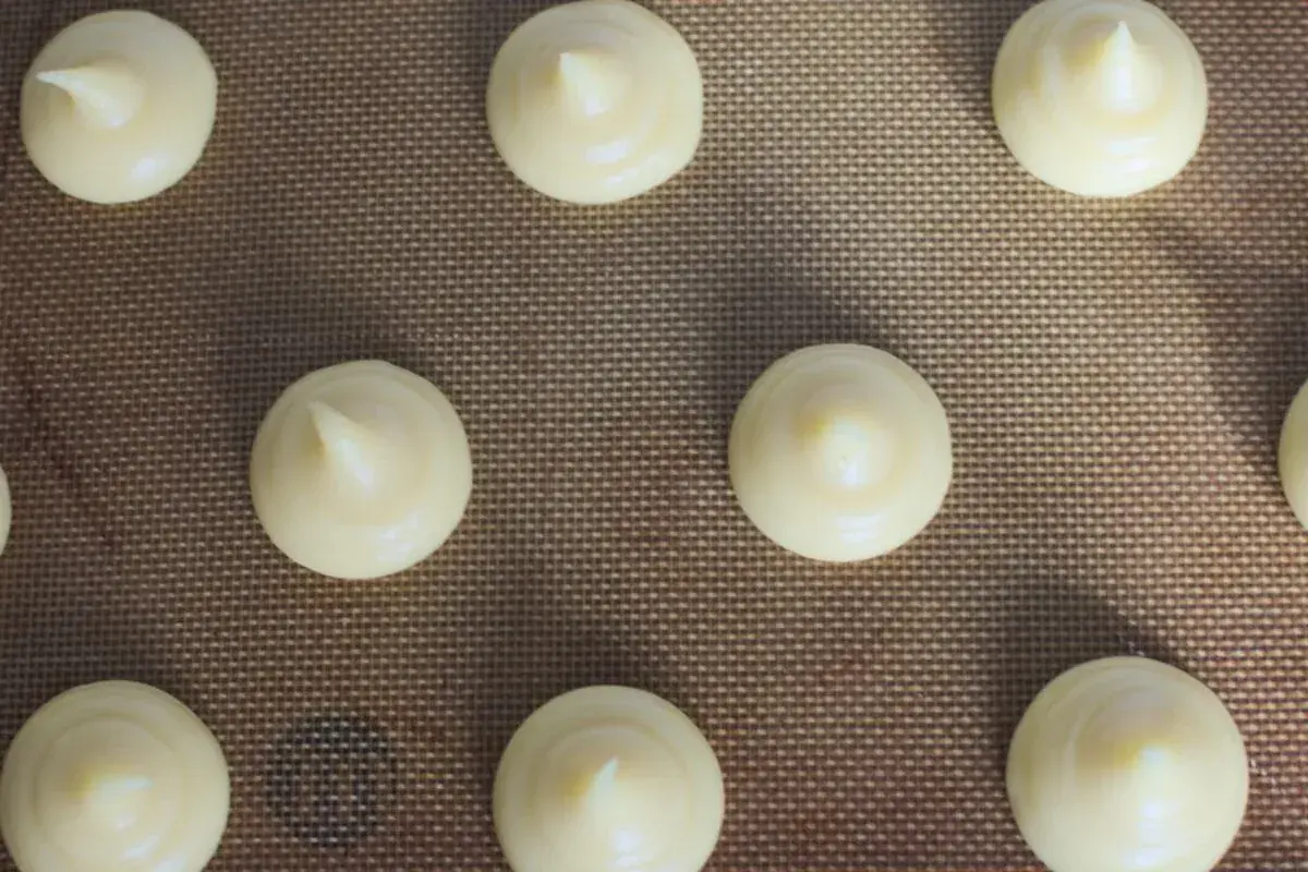 Chouquettes prêtes à cuire sur une plaque. Pour bien conserver des chouquettes, il faut les laisser refroidir complètement avant de les stocker.
