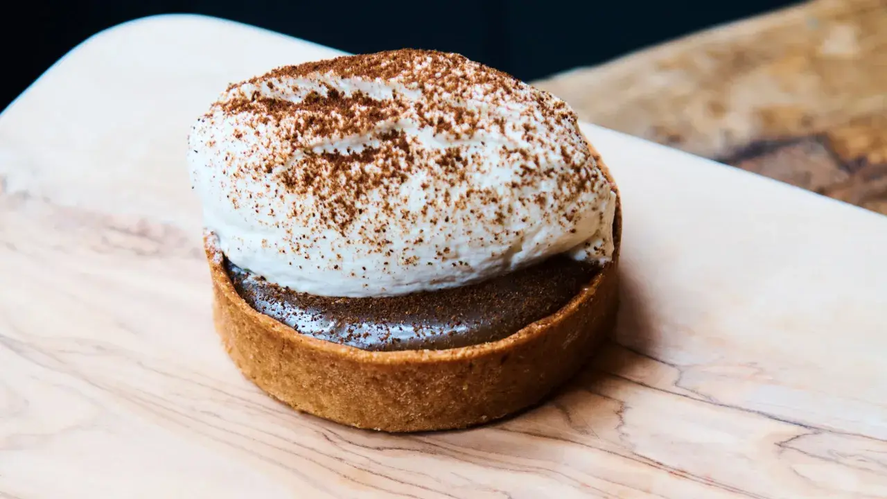 Tartelette gourmande avec une généreuse crème pour gâteau, saupoudrée de cacao. Un délice visuel.