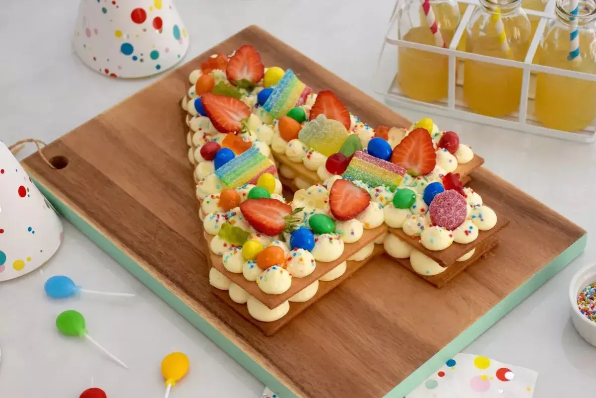 Un délicieux number cake sans crème, décoré de fraises, bonbons et vermicelles colorés, parfait pour une fête d'anniversaire.