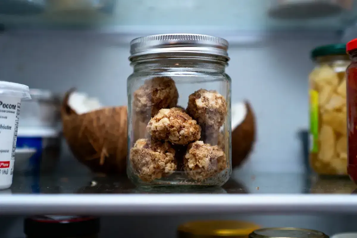 Bocal de conservation de rochers coco, une collation saine et gourmande, à côté d'une noix de coco ouverte.