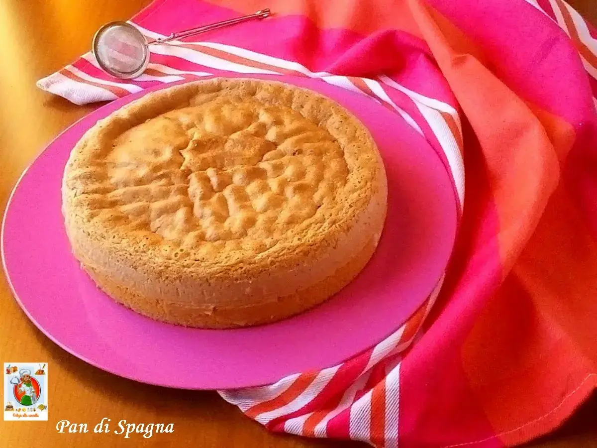Un gâteau "Pan di Spagna" sur une assiette rose, prêt pour la conservation génoise. Un tamis est à côté.