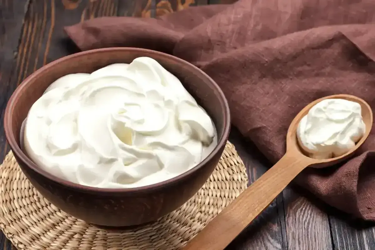 Crème diplomate onctueuse dans un bol, prête pour une recette gourmande. Une cuillère en bois en présente une portion.
