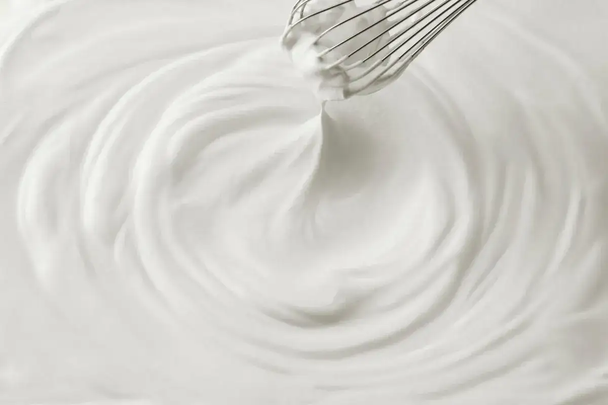 Un fouet en train de battre de la chantilly maison, créant des vagues douces et aériennes dans la crème.