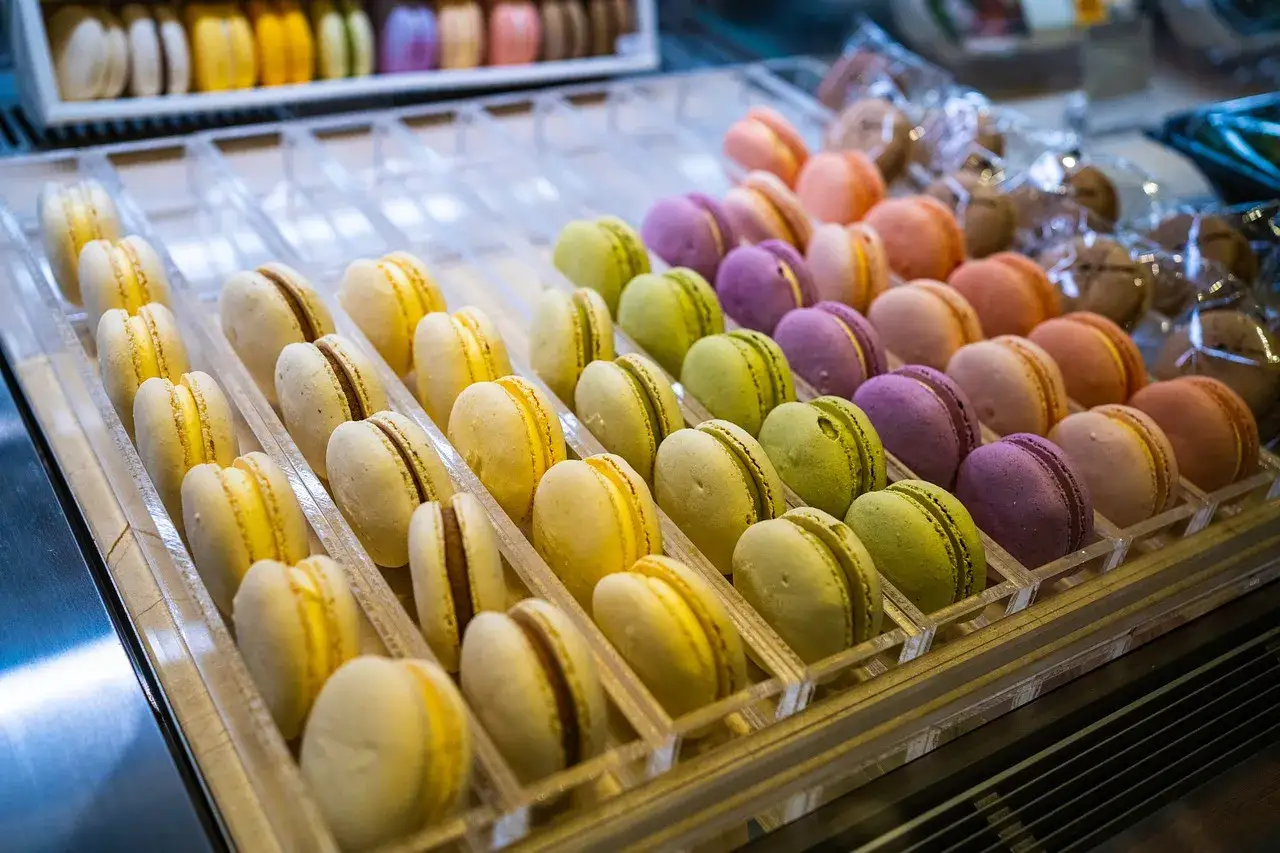 Des macarons colorés, parfaits ingrédients patisserie, alignés dans des présentoirs transparents.