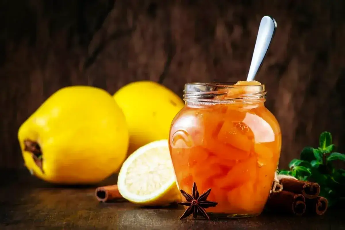 Confiture de coings aux épices, une touche de gelatine pectine pour une texture parfaite. Des coings jaunes, un citron, de la cannelle et de l'anis étoilé complètent la scène.