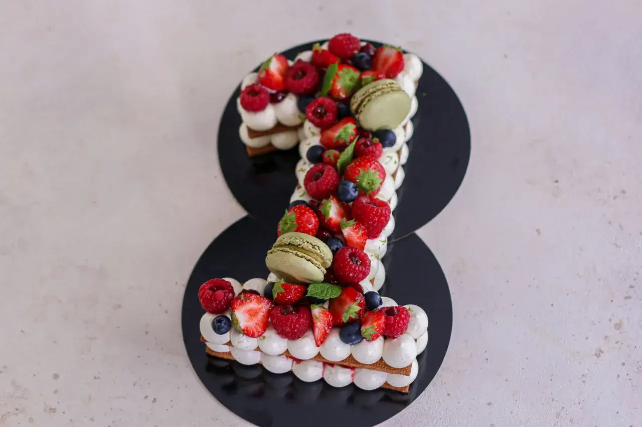 Un délicieux number cake en forme de 1, garni de fruits rouges frais et de macarons verts. Une création légère et gourmande, sans crème.