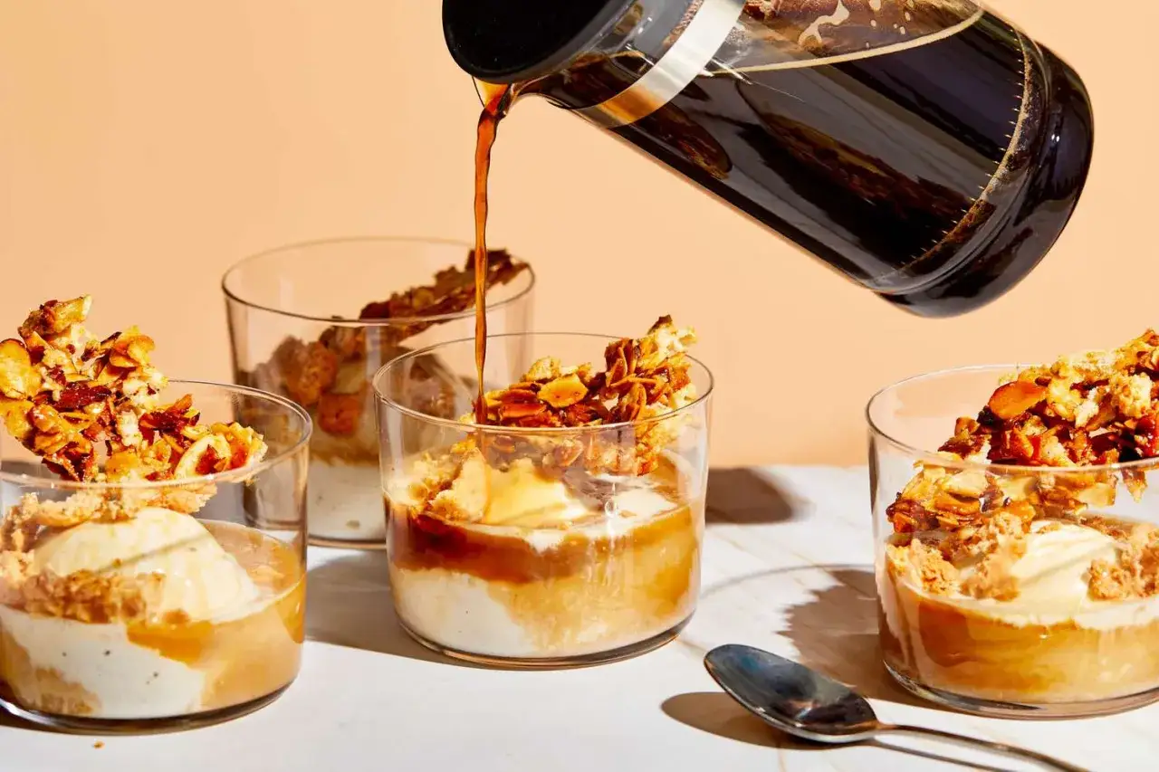 Café chaud versé sur un dessert sans cuisson : glace, crumble et amandes caramélisées dans des verres.