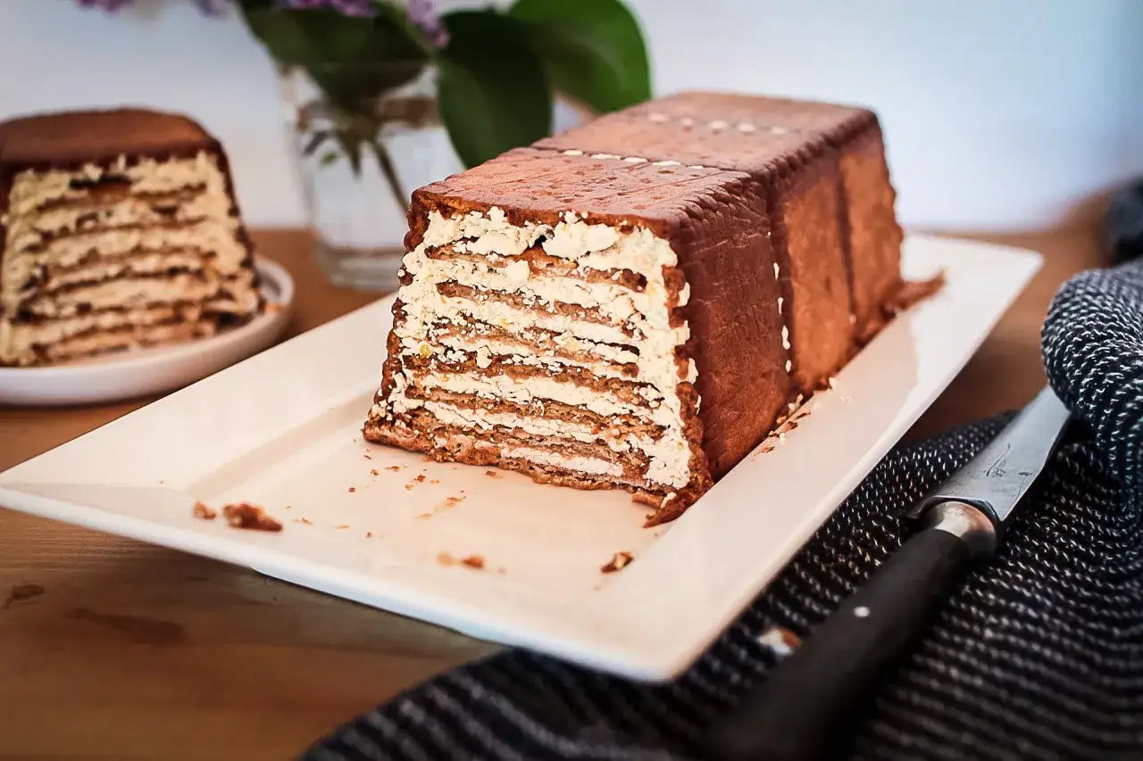 Un délicieux gâteau biscuit, avec des couches de crème et de biscuits, recouvert de chocolat. Un autre gâteau similaire est visible en arrière-plan.