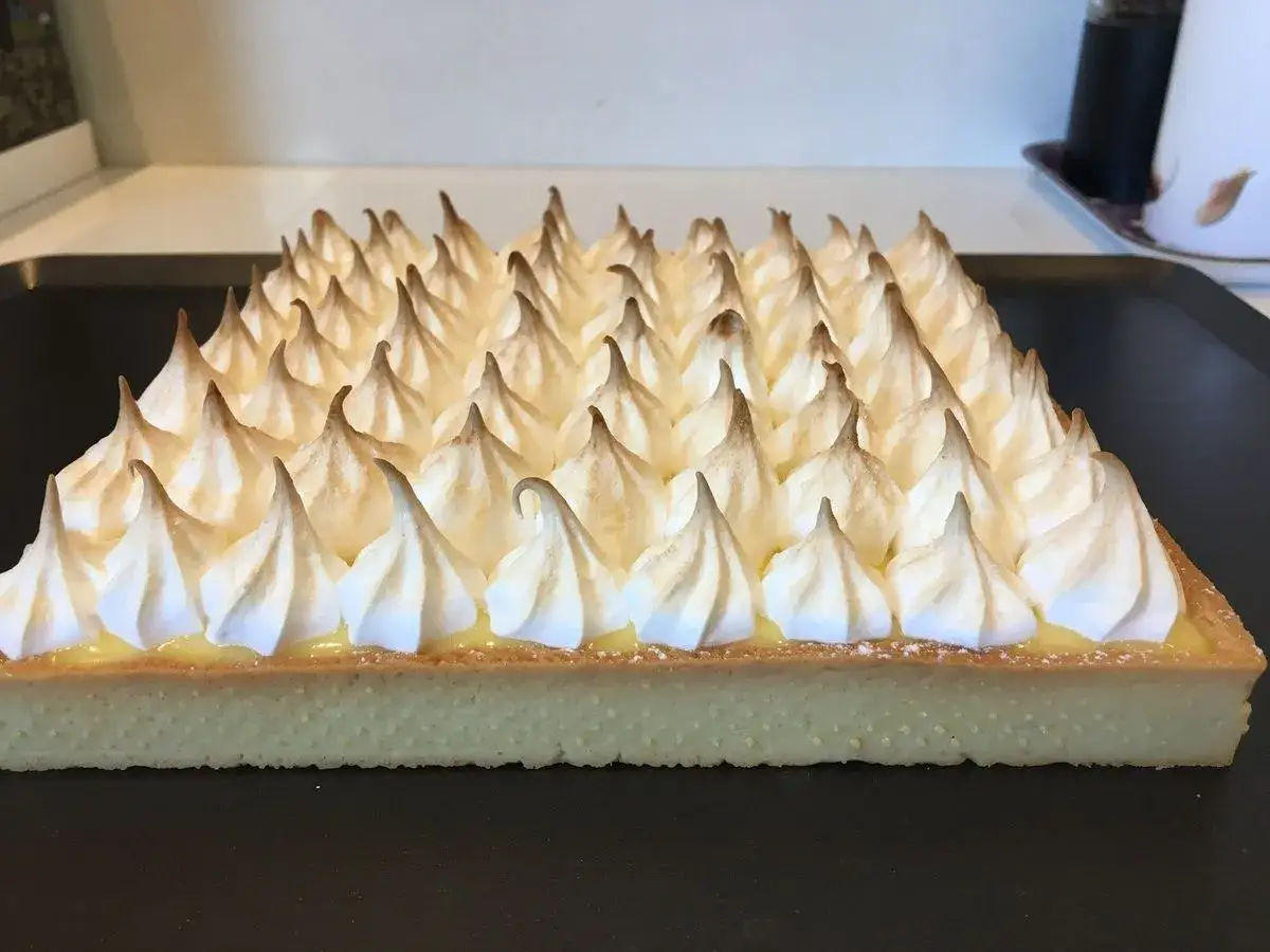 Tarte citron meringu&eacute;e Pierre Herm&eacute;, une &oelig;uvre d'art gourmande aux pointes de meringue dor&eacute;es.