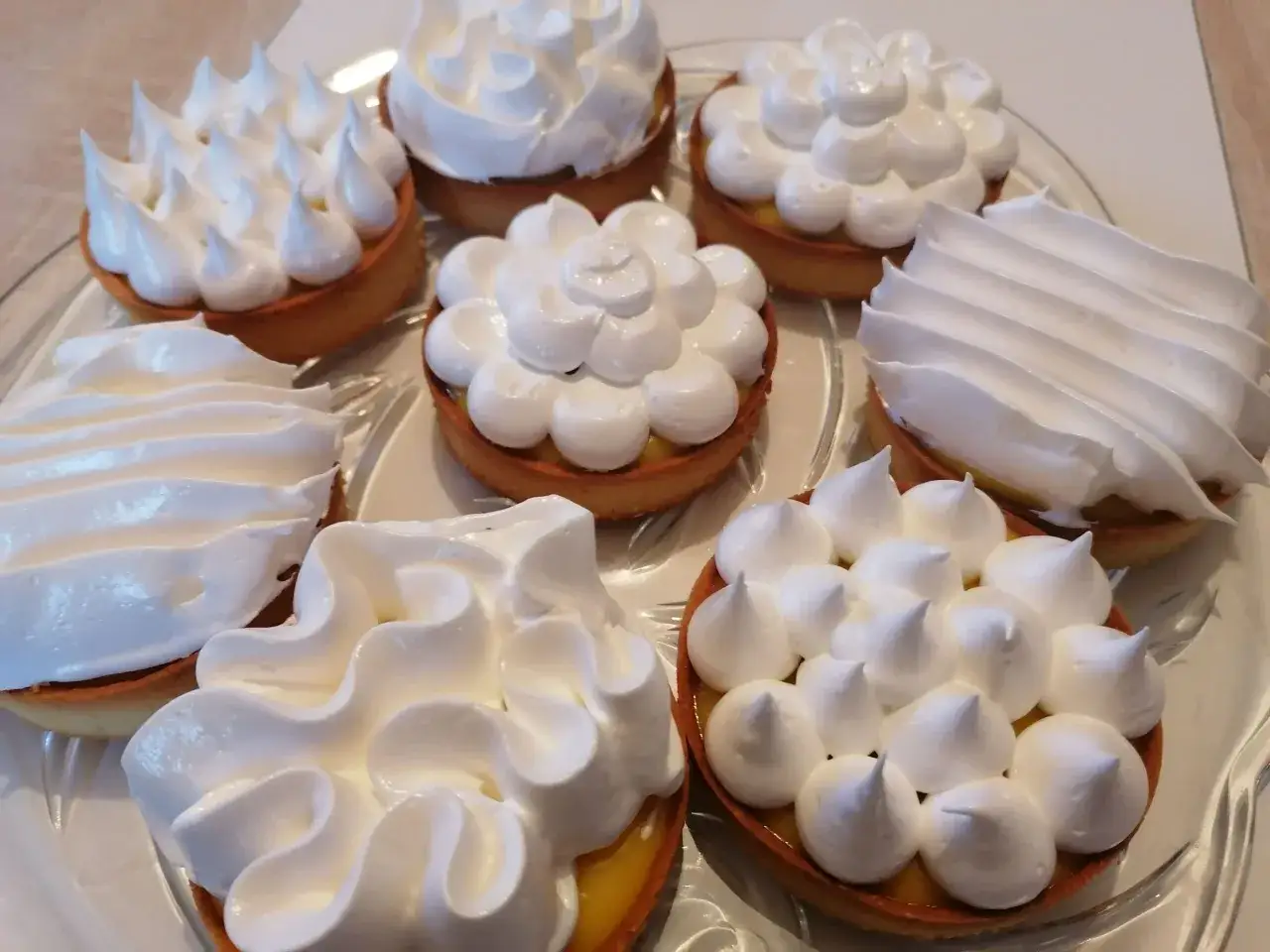 Plateau de tartelettes garnies de crème citron et couronnées de meringue italienne, une œuvre d'art culinaire.