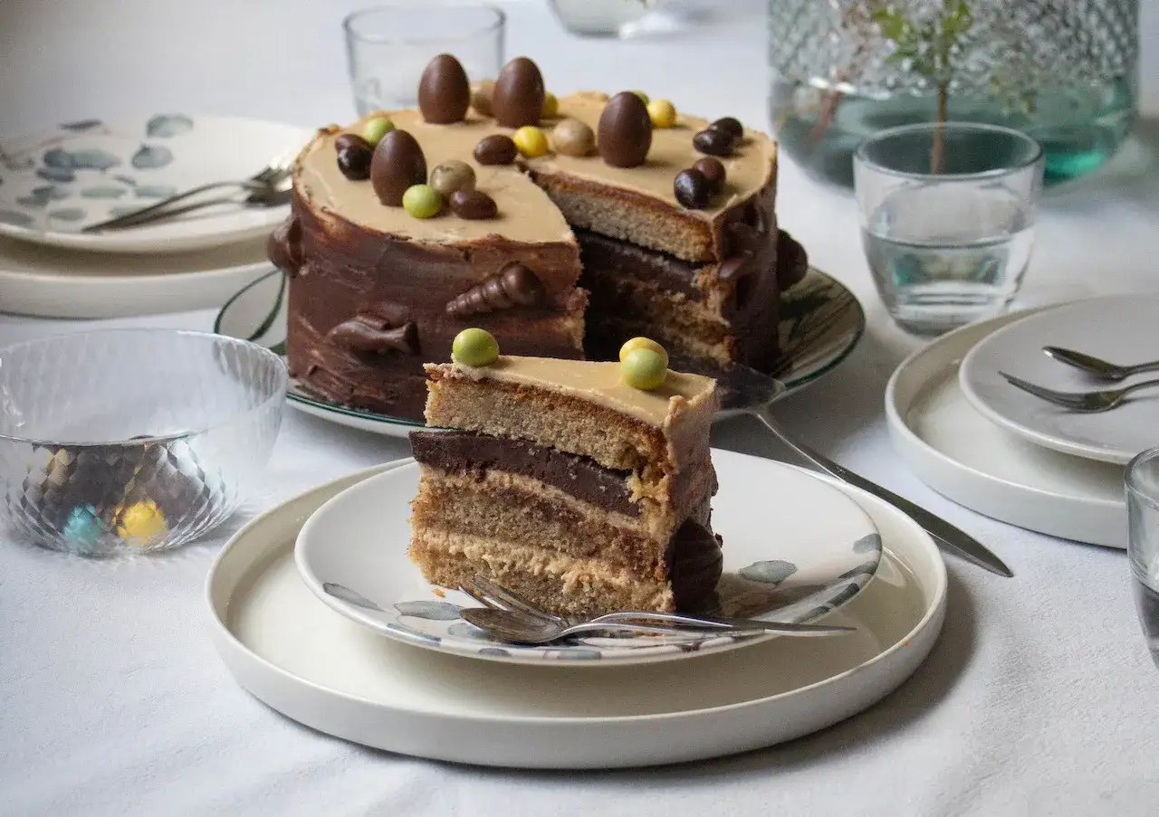 Un délicieux gâteau praliné, décoré d'œufs en chocolat, est servi sur une table dressée pour Pâques.