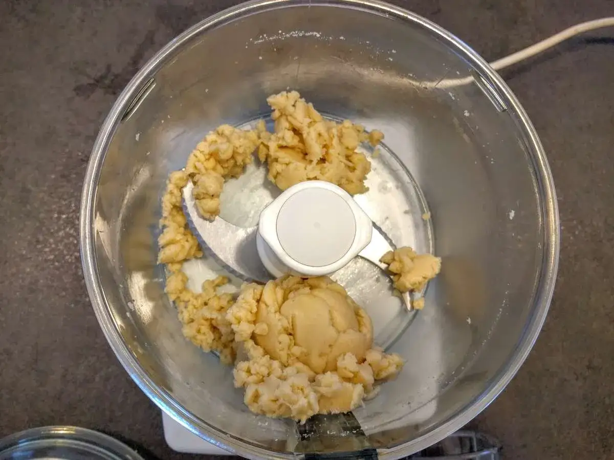 Pâte d'amande maison dans un robot culinaire, prête à être façonnée.