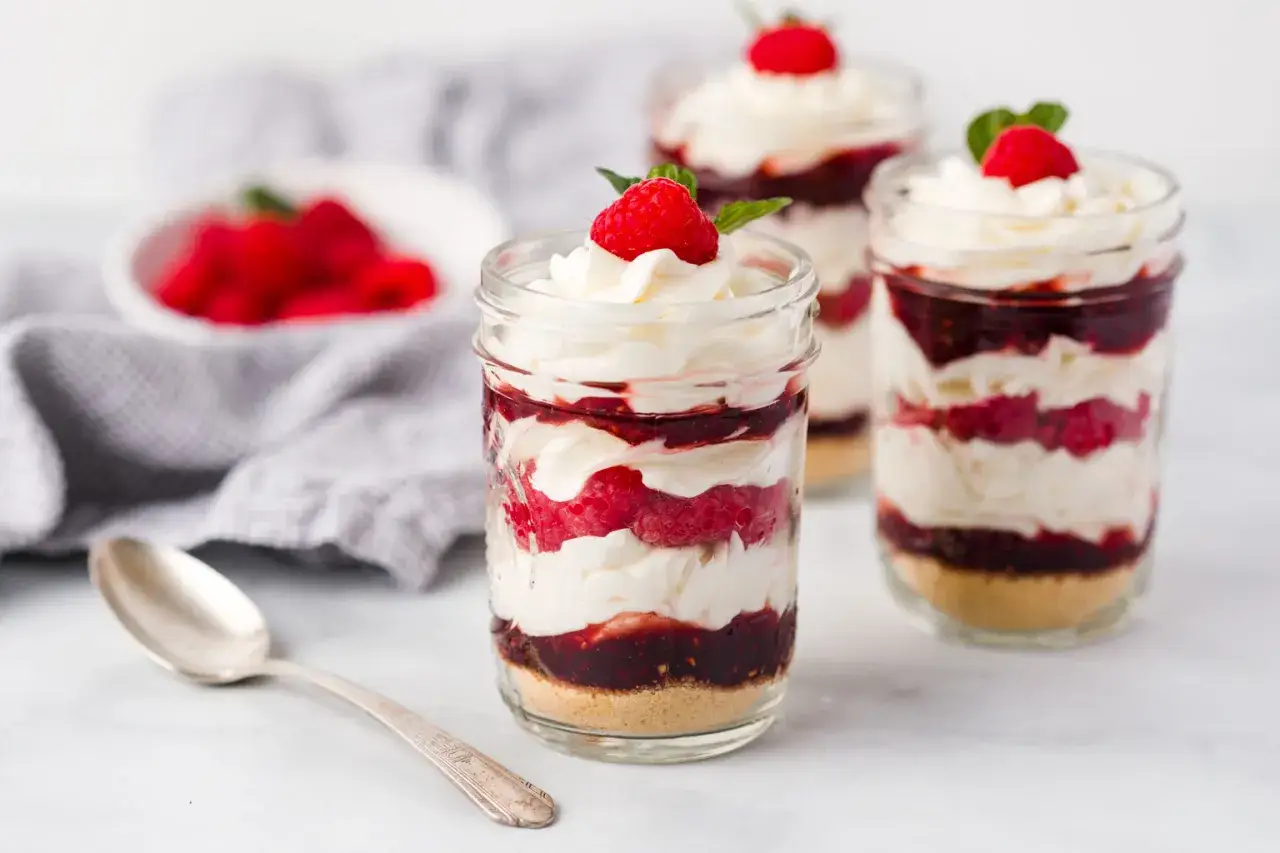 Desserts en pot : couches de biscuit, framboise pectine, crème fouettée et garniture de framboise.
