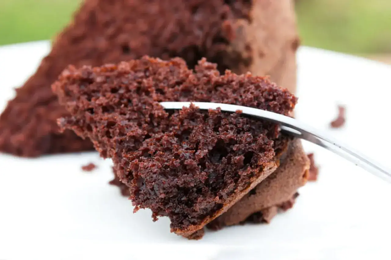 Une tranche de fondant chocolat sans beurre, moelleuse et aérienne, est piquée par une fourchette.