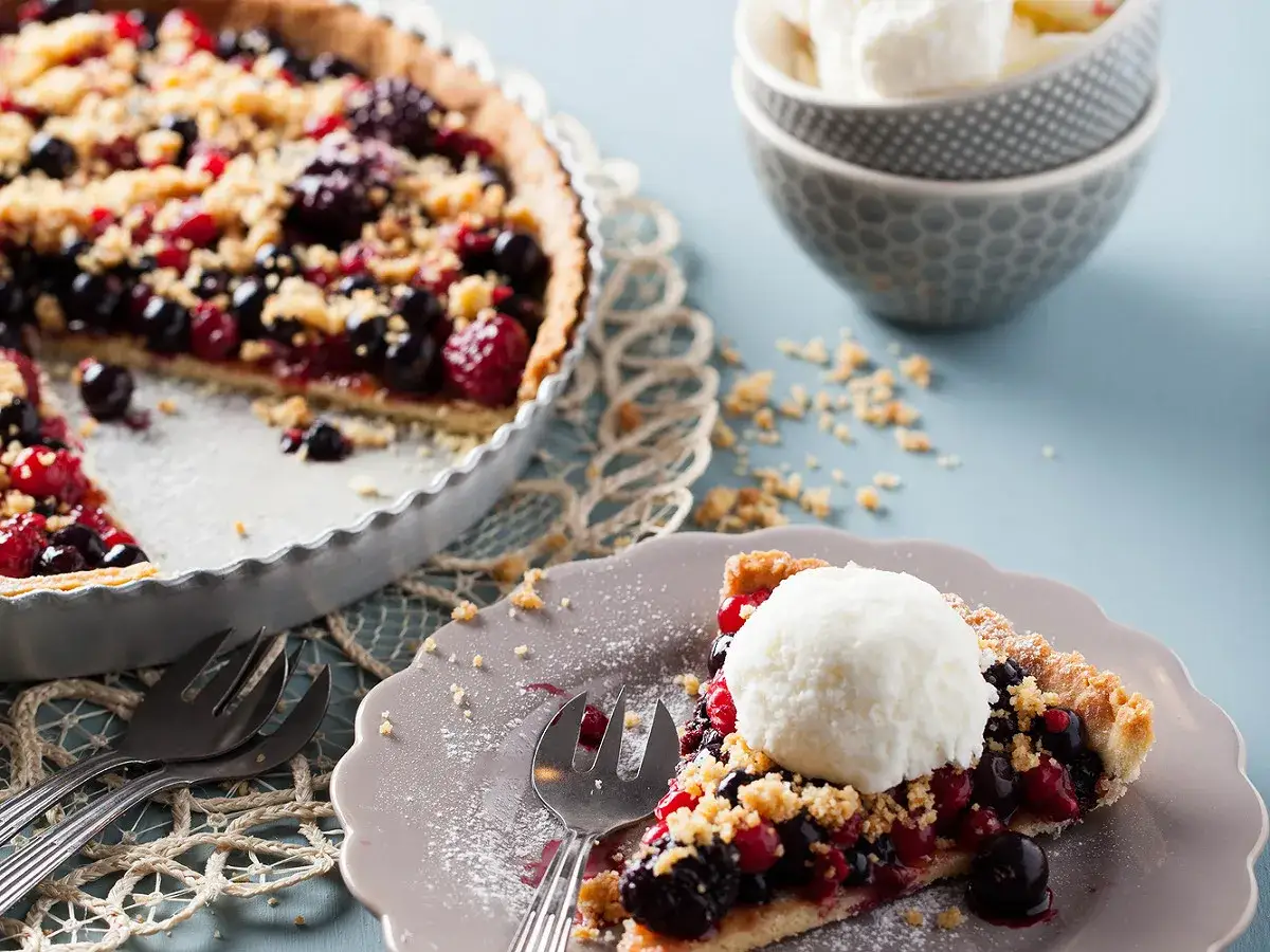 Une part de tarte aux fruits rouges, garnie d'une boule de glace, un délice de saison.