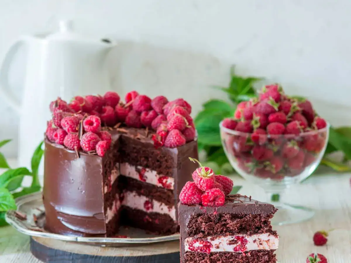 Gâteau au chocolat et framboises, une décoration gateau facile et gourmande. Une part coupée révèle la garniture crémeuse et fruitée.