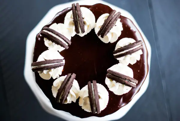 Gâteau au chocolat glacé, décoré de crème fouettée et de biscuits Oreo. Un délice pour les amateurs de layer cake Oreo.